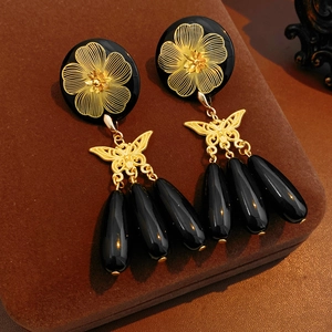 Detailed macro view of vintage butterfly earrings with black teardrop bead tassels