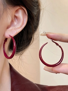 Close-up of elegant burgundy red enamel hoop earrings with silver pins for women