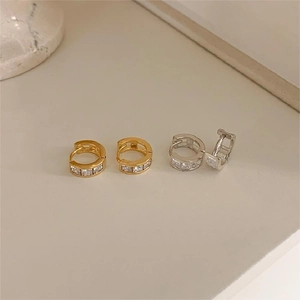 Close-up of gold and silver hoop earrings featuring square-cut cubic zirconia insets