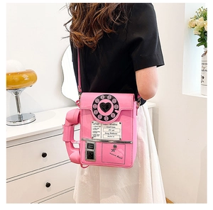 Detail of pink vintage telephone crossbody bag with Hotline lettering on a model