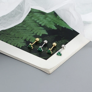 Close-up of gold and silver S925 four-leaf clover stud earrings with green gemstones