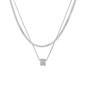 Detail of layered silver necklace with flat snake chain and minimalist cube pendant