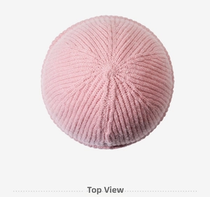 Vue de dessus du bonnet en tricot rose montrant la texture côtelée douce et le tissage