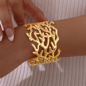 Detailed view of gold multi-layer coral texture cuff bracelet on textured knit fabric
