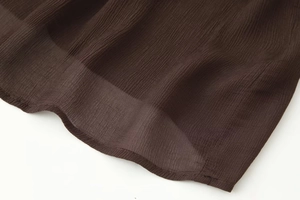 Détail de l'ourlet en mousseline marron foncé léger avec une finition texturée fine