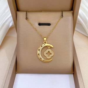 Macro shot of gold crescent moon and clover necklace with zircon in a premium gift box