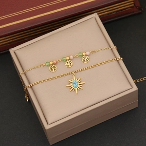 Detailed shot of double-layered gold necklaces with tree pendants and star sunburst charm