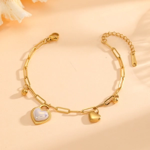 Detail of gold paperclip chain bracelet with shell heart pendant and S-STEEL tag