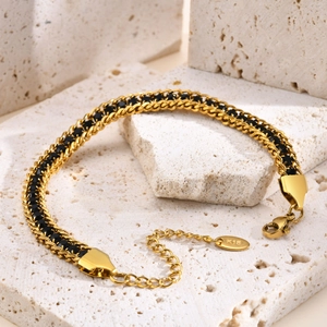 Detail of double-layer golden chain bracelet with black zircons and K18 tag