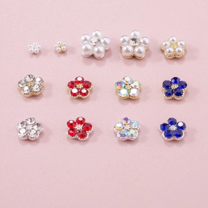 Macro shot of 3D nail art charms with colorful five-petal flowers and pearls