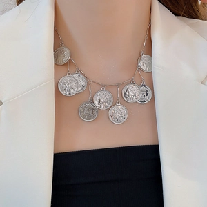 Close-up of silver coin multi-pendant necklace with vintage portraits on a white blazer
