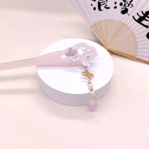 Detail of pink flower acetate hair pin with butterfly charms and pearl tassels