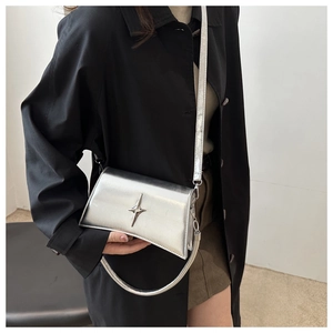 Elegante borsa a tracolla argento con logo a stella indossata su cappotto nero