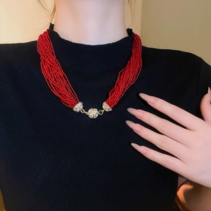 Detail of red multilayer beaded necklace with sparkling golden rhinestone accents