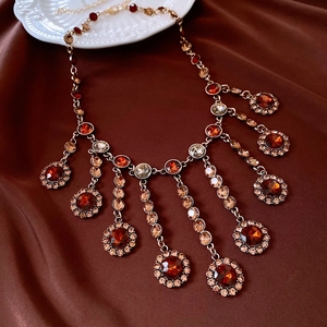 Détail d'un collier vintage doré avec cristaux rouges et champagne sur soie brune