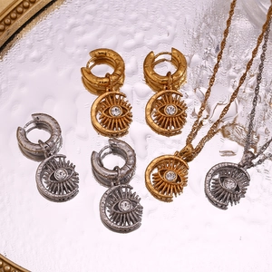 Detailed view of evil eye and crescent moon pendants on a reflective water drop surface