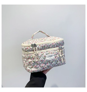 Floral quilted cotton makeup bag featuring dual zippers with tassels and top handle