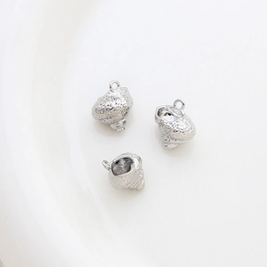 Macro detail of three silver conch shell pendants for DIY jewelry on white surface
