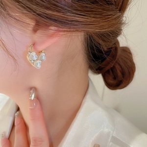 Macro detail of gold plated heart hoop earrings featuring tiny white zircon flowers