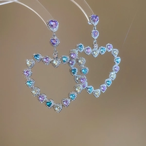 Détail de boucles d'oreilles cœur en argent avec pierres colorées et reflets brillants