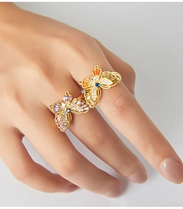 Close-up of elegant gold butterfly rings with colorful crystals worn on a model hand