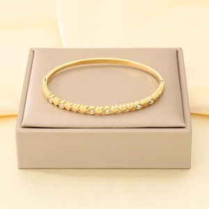 Vista ravvicinata di un bracciale in acciaio inossidabile dorato con cuori e cristalli