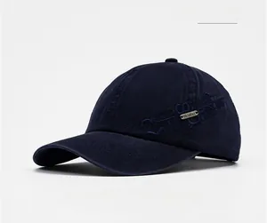 Detail of navy blue washed baseball cap featuring a metal logo and sport embroidery