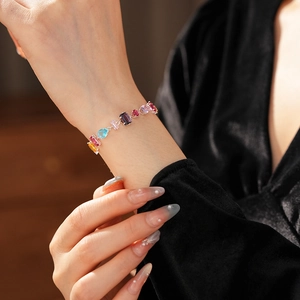 Close-up of a silver bracelet with multi-colored gemstones on a model wrist