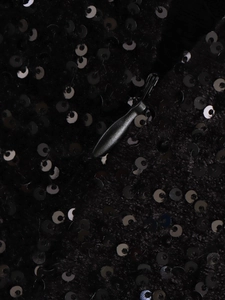 Vista macro del tessuto con paillettes nere e chiusura a cerniera invisibile abbinata