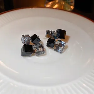 Modern geometric crystal stud earrings with black and grey square stones on a tray