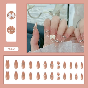 Detail of pink long ballerina press-on nails with 3D white bows and pearl rhinestones