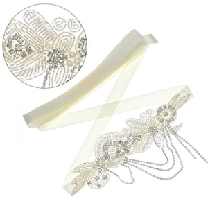 Macro detail of hand-sewn rhinestones and beads on a bridal ivory satin belt sash