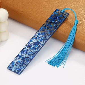 Macro detail of blue glitter resin bookmark with a matching silk tassel on leather