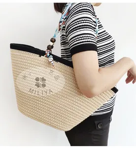 Detail of woven straw tote bag featuring silk scarf handle and vintage wooden beads