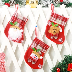 Three Christmas stockings with Santa, Snowman, and Bear dolls on white fence background