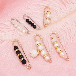 Elegant pearl and rhinestone decorative safety pin set on pink feather background