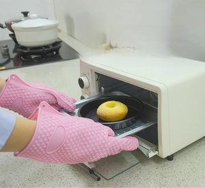 Close-up of pink silicone oven mitt with anti-slip texture removing food from an oven