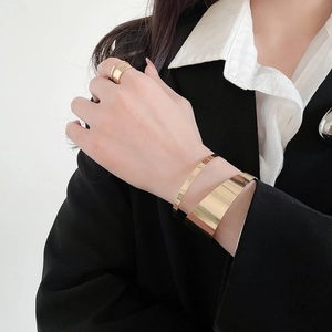 Polished gold minimalist hollow bangle set with matching ring on model in black suit