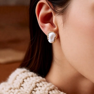 Close-up of vintage oval pleated gold earrings with white stones and crystal accents