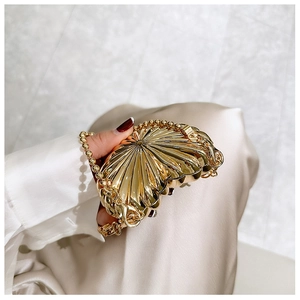 Close-up of golden shell-shaped evening bag with pleated metallic texture and chain
