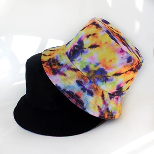 Detail view of foldable bucket hats in solid black and vibrant tie-dye patterns