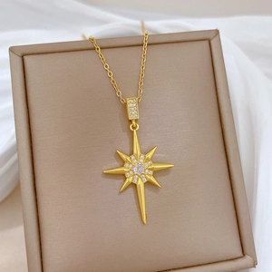 Detail of gold starburst necklace with clear rhinestones on a beige display