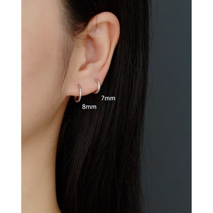Close-up of minimalist 925 silver hoop earrings in 7mm and 8mm sizes worn by a model