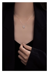 Close-up of a 925 sterling silver letter necklace with a dancing zircon on a model