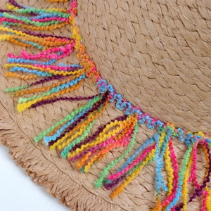Detailed macro view of colorful fringe tassels on a woven straw beach sun hat