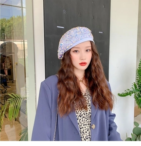Detailed view of white beret featuring colorful shimmering sequins and iridescent pearls