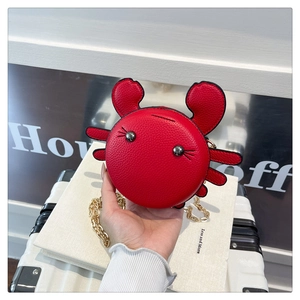 Close-up of red crab shaped coin purse with gold chain and pebble leather texture