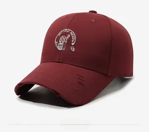 Detail of distressed brim and white embroidery on burgundy cotton baseball cap