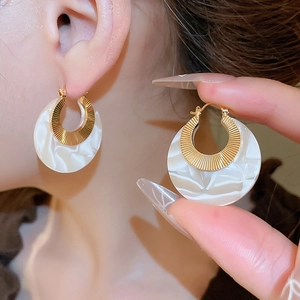 Detail of round acetate marble hoop earrings with gold inner textured metal ring