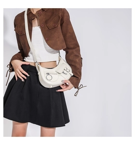 Détail du sac demi-lune en similicuir blanc cassé avec anneaux en métal et boucles